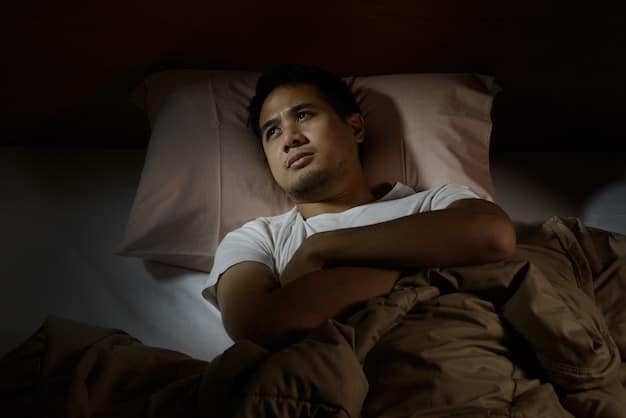 A Mexican man tossing and turning in bed at night, unable to sleep. His eyes are wide open and he appears anxious.  The room is dark, with only a faint glow from the moon coming through the window.
