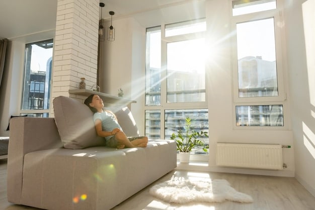 A sunlit living room with large windows open, allowing fresh air and natural light to flood the space. The decor is light and airy, with white walls, sheer curtains, and green plants. A comfortable sofa is positioned near the window, inviting relaxation.