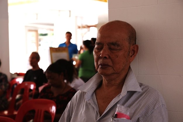 An empowering scene showing an elderly Mexican man confidently teaching a group of younger individuals how to play a traditional board game, showcasing intergenerational connection and knowledge sharing.