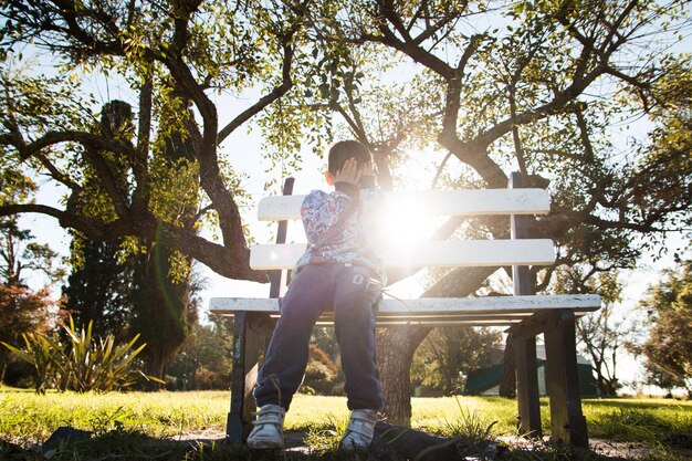 Close-up of a Mexican couple holding hands while sitting on a park bench, with sunlight filtering through the trees in the background. Their hands clasped together symbolize support and affection.