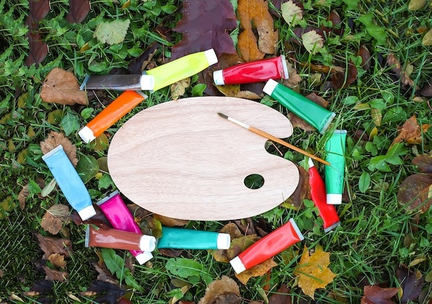 A close-up shot of various non-toxic acrylic paint tubes and brushes organized on a table, ready for use in painting a mural, with a color palette inspired by Frida Kahlo.
