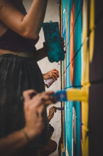 A person's hands creatively painting a mural on a wall, using fingers to add unique textures and details to a design inspired by Frida Kahlo's style.