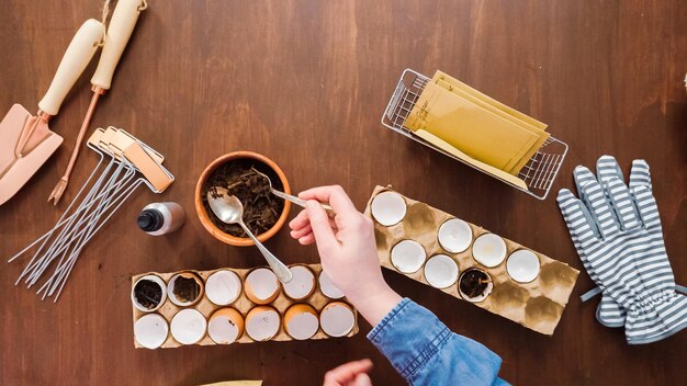 A well-organized workspace showing a person in the process of grating a bar of homemade soap, with various tools and ingredients neatly arranged around them, including coconut oil, essential oils, and dried herbs.