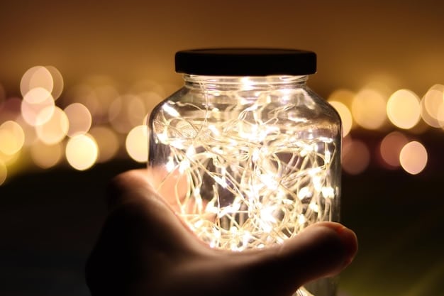 Close-up of hands carefully wrapping LED string lights around a clear glass bottle to create a decorative lamp. Tools and materials are neatly arranged on a workbench.