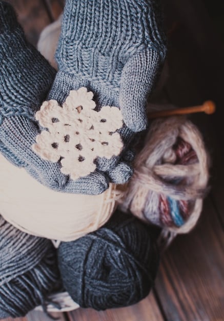 A person wearing a hand-knitted chunky wool hat and scarf in a snowy outdoor setting, showcasing the fashion and function of the knitted items.
