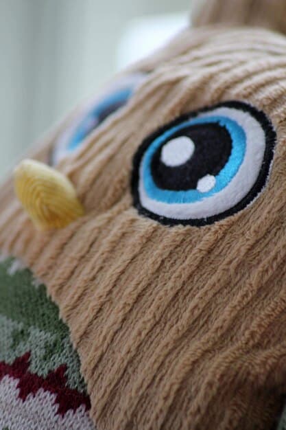 A close-up of a finished rag doll face with carefully sewn button eyes, embroidered details for the nose and mouth, and yarn hair, showcasing the intricate details and personalization that goes into making each doll unique.