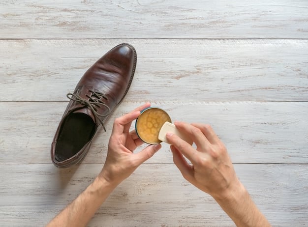 Close-up of a hand polishing a leather shoe with a soft brush after applying beeswax. The shoe has a noticeable sheen from the beeswax.