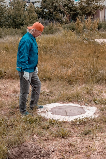 A medium shot showing a person gently sanding a small area around a hole in a wall after applying toothpaste, using a fine-grit sandpaper block. The focus is on the smoothing process and the texture of the wall.