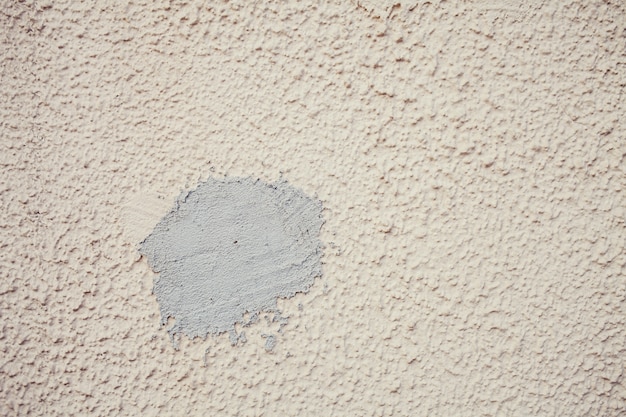 A close-up, slightly angled shot of a repaired wall. The small hole is now filled and smoothly blended with the surrounding wall, with a texture that matches the existing paint.