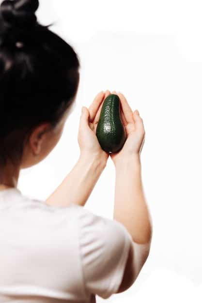 A photo of a hand gently pressing a ripe avocado to check for ripeness, with other avocados in the background. Focus on the texture and color of the avocado being tested.