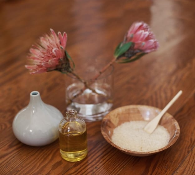 A close up of small bottles of essential oils, with baking soda in a glass bowl. The background is blurred. The focus is on the essential oils.