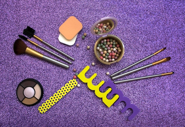 A set of makeup brushes, displayed in a disorganized manner, coated in different colors of makeup. Powder residue sits on the brush handles. The photo is a close-up to highlight the buildup on the bristles.
